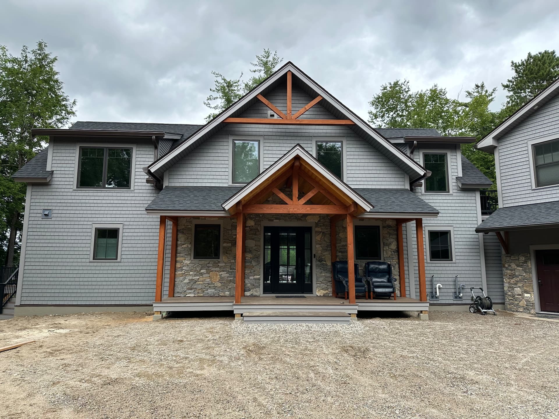 Completed shingle-style custom home with timber frame entry and stone accents
