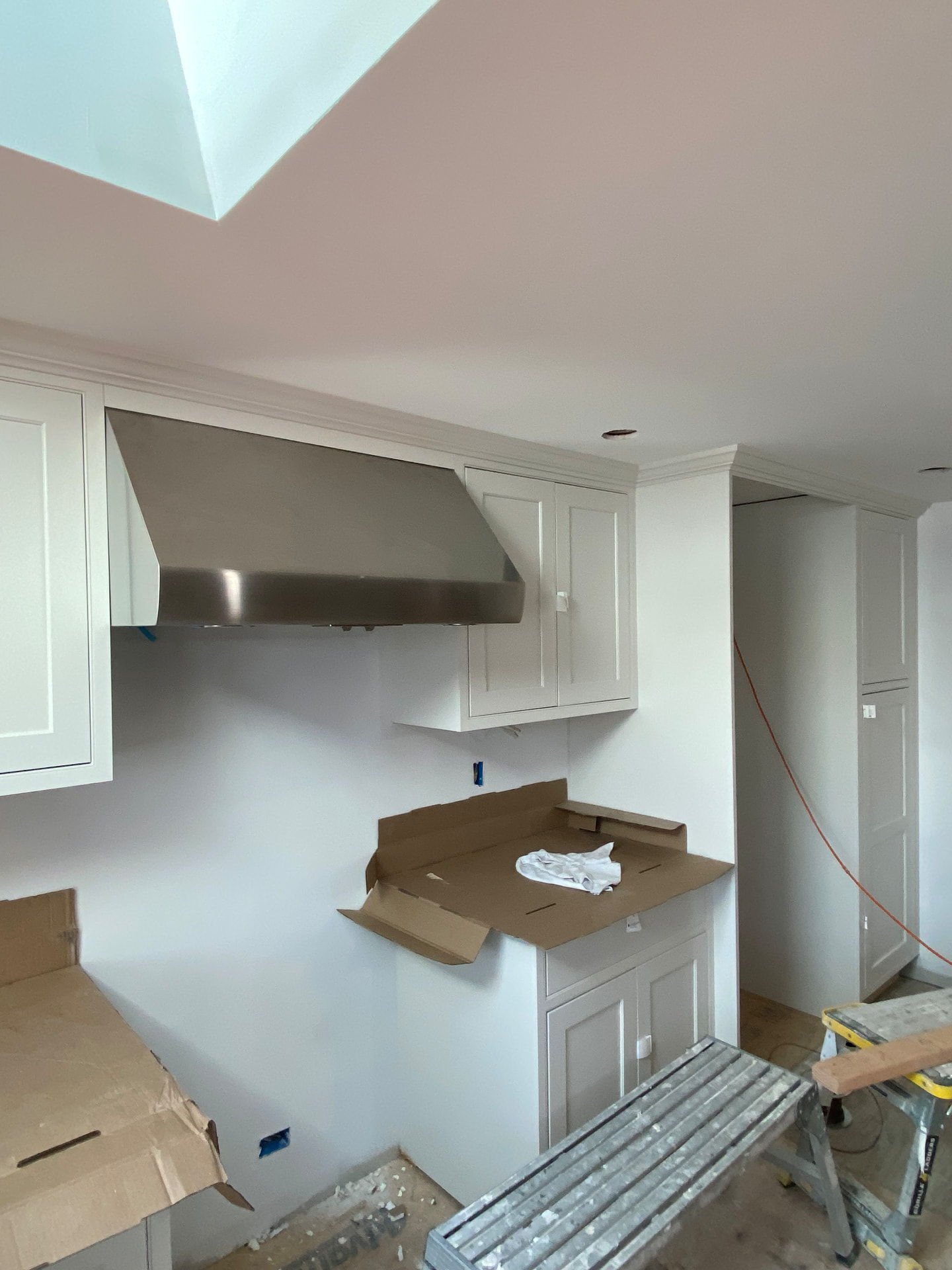 Stainless range hood and custom cabinetry in a kitchen renovation