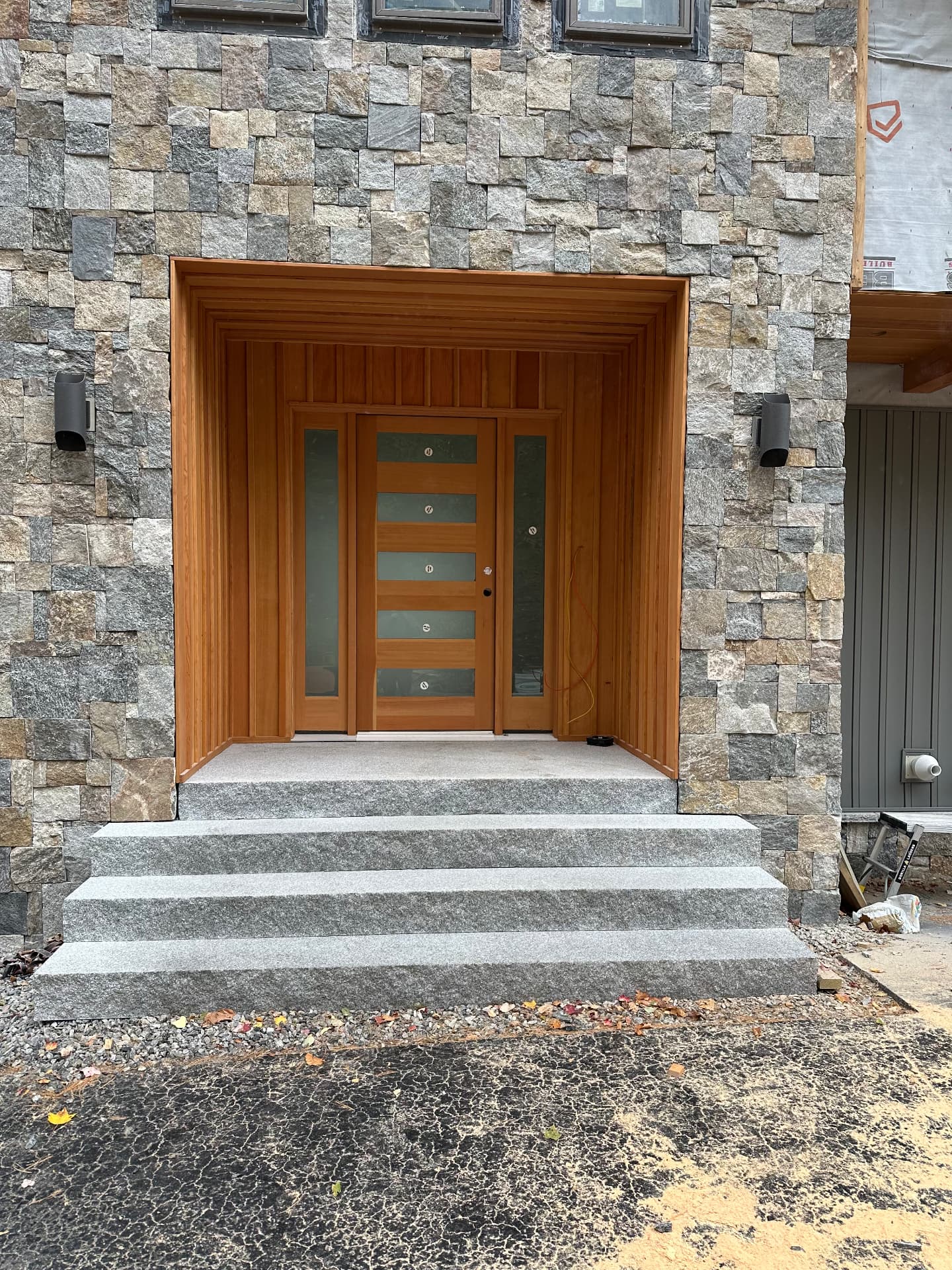 Custom entry with natural stone veneer, fir surround, and granite steps